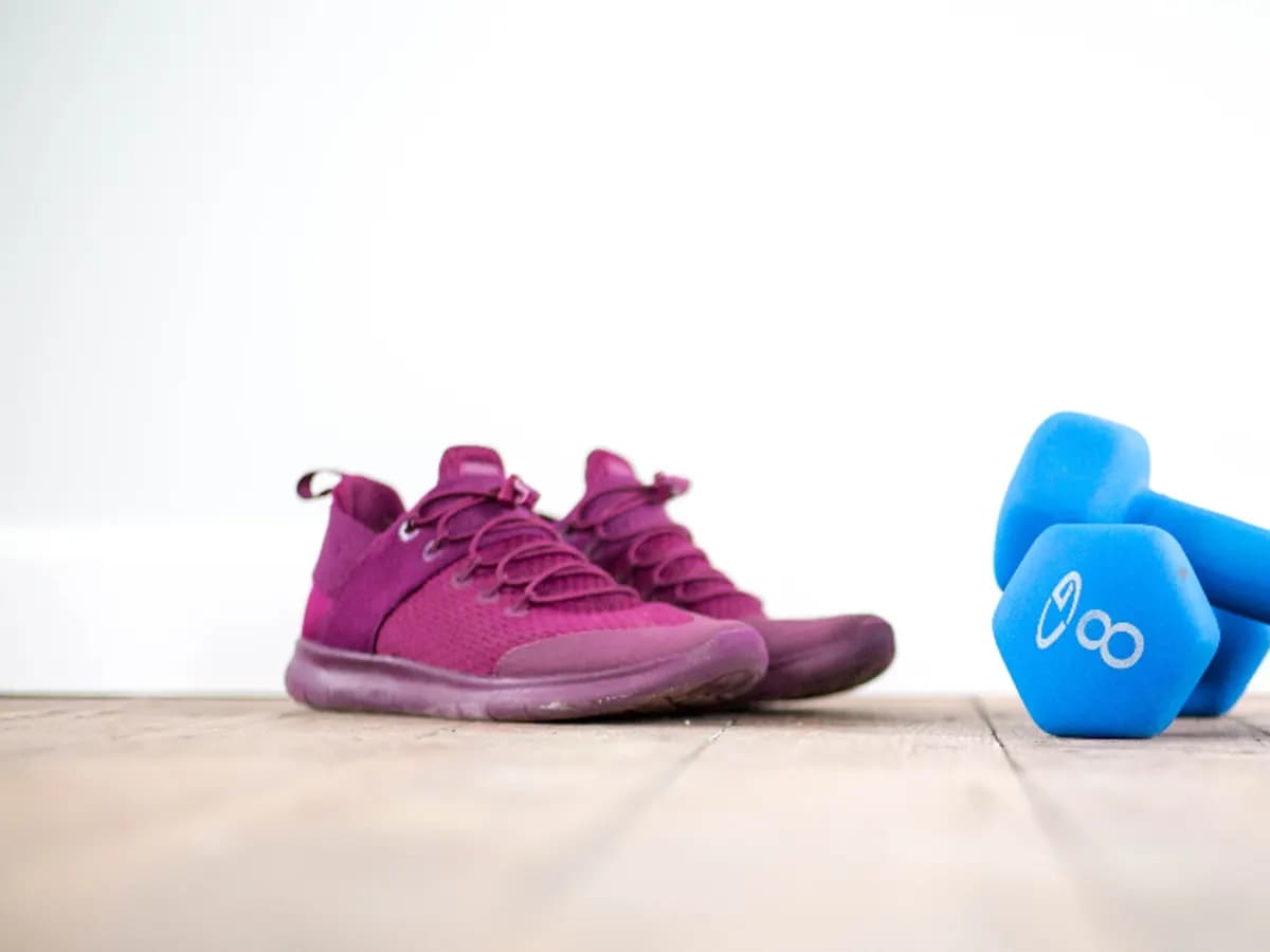 A pair of dumbbells and sneakers on a wooden floor